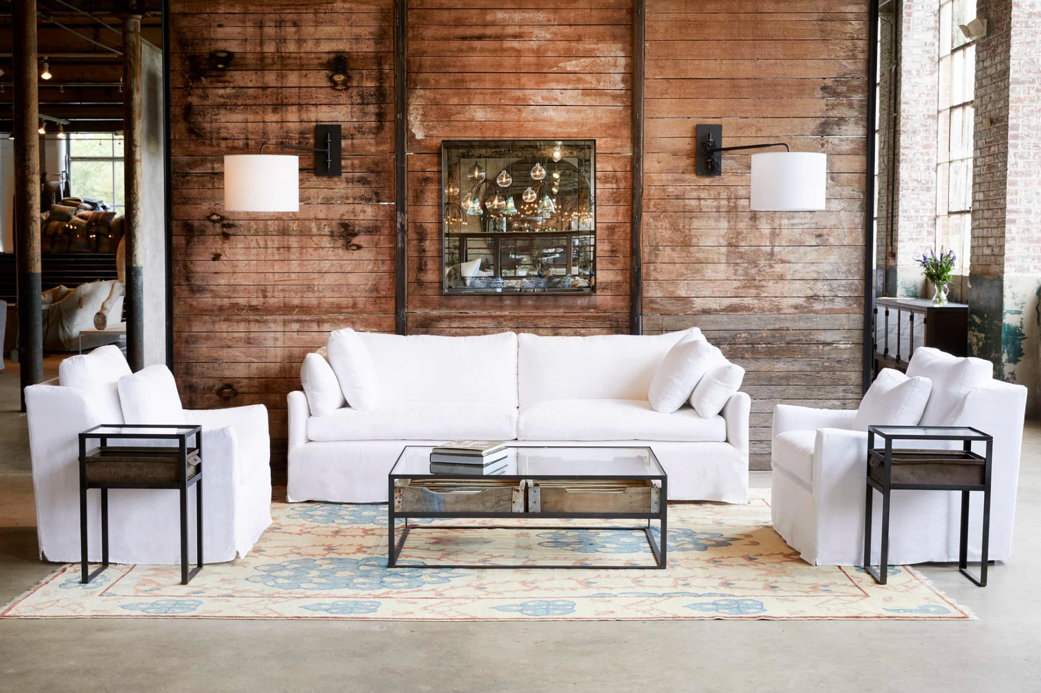 Modern living room with the Caicos white slipcovered sofa, chairs, and coffee table in front of a wooden wall Our Boat house