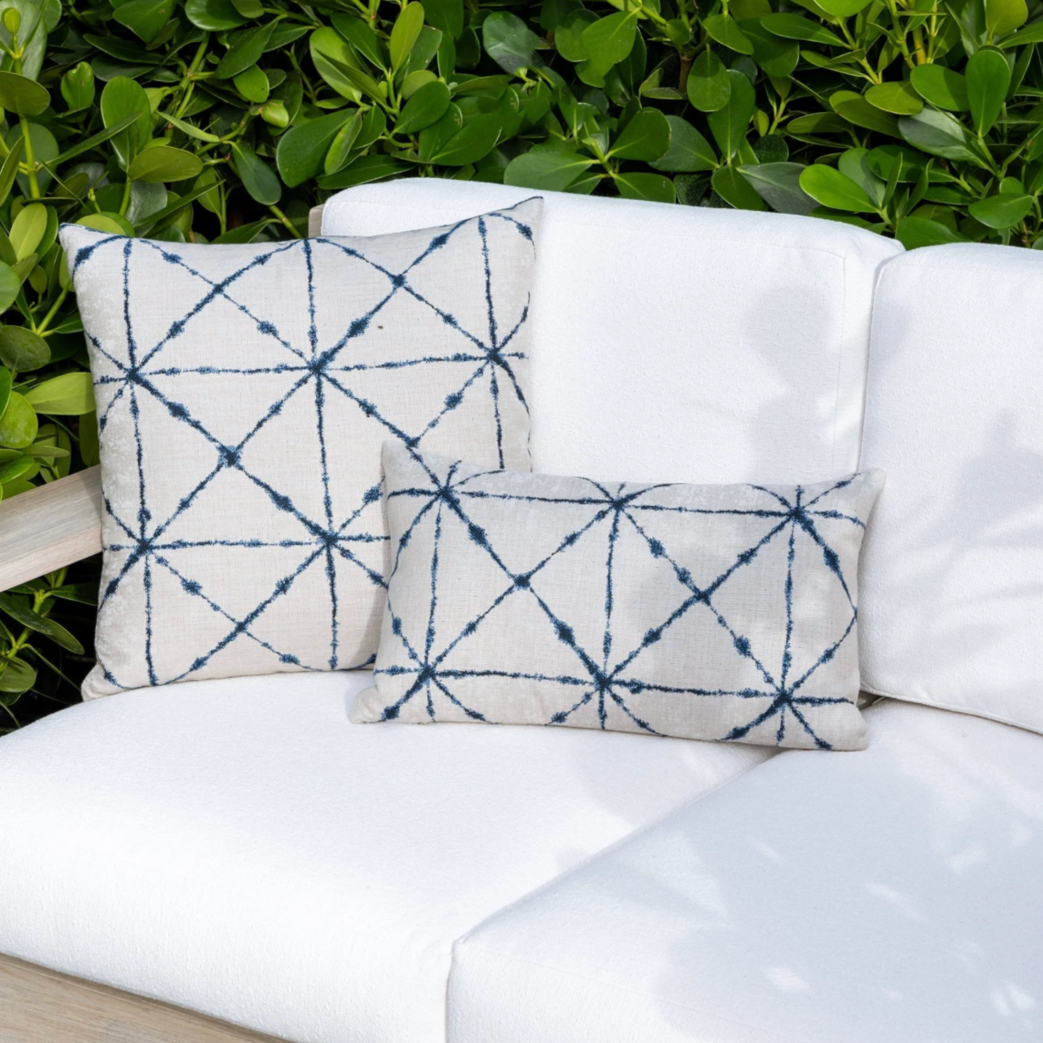 indigo and white diamond pattern throw pillow layered on neutral sofa in coastal living room lifestyle