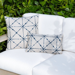 indigo and white diamond pattern throw pillow layered on neutral sofa in coastal living room lifestyle