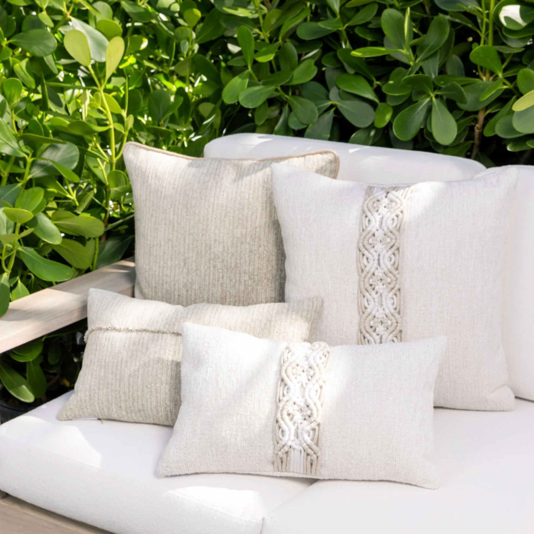 textured chenille and macrame throw pillow in neutral tones layered on sofa in coastal living room lifestyle