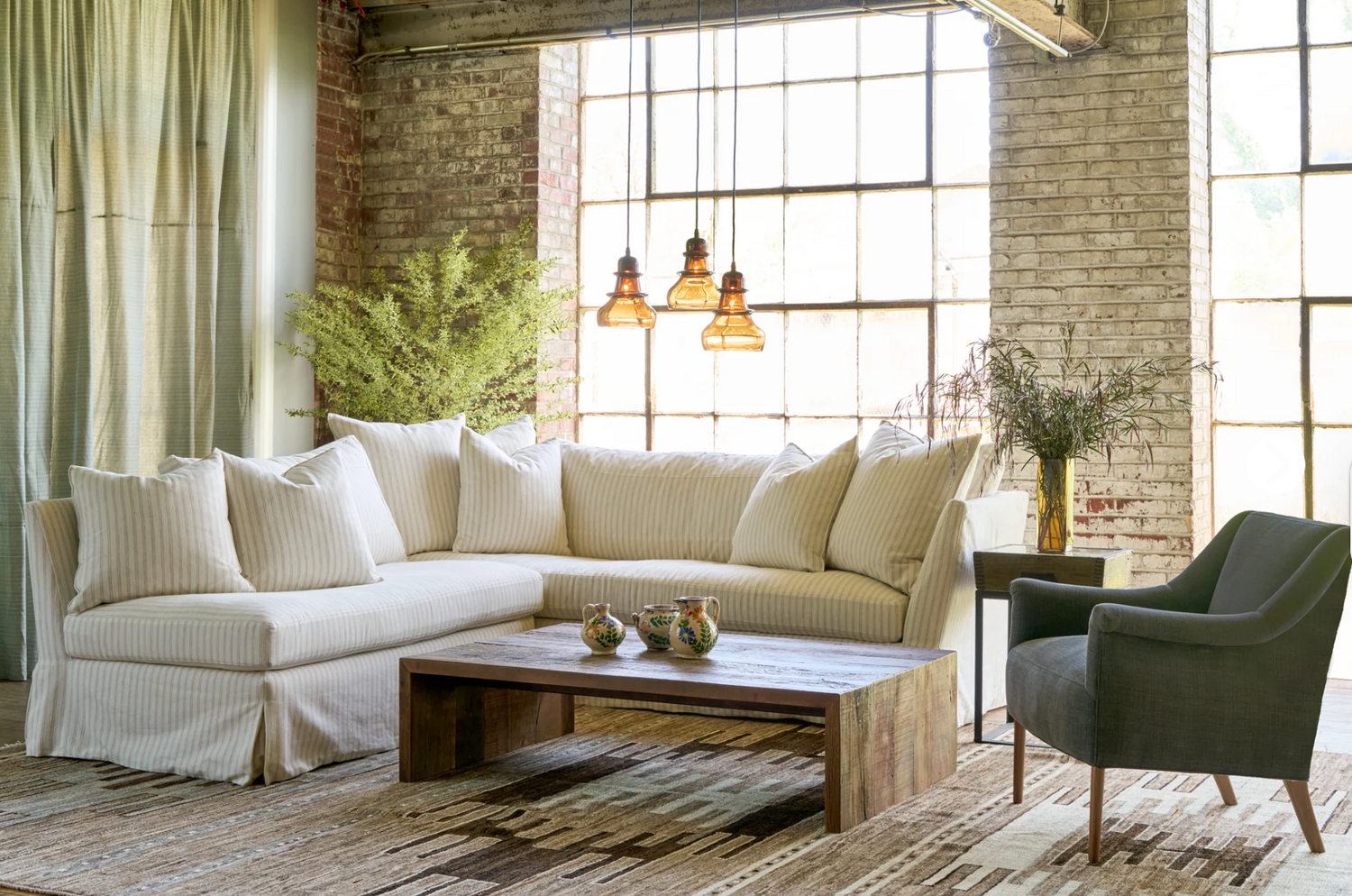 Neutral living room with a St. Barts Slipcovered sectional sofa, coffee table, and armchair from Our Boat House