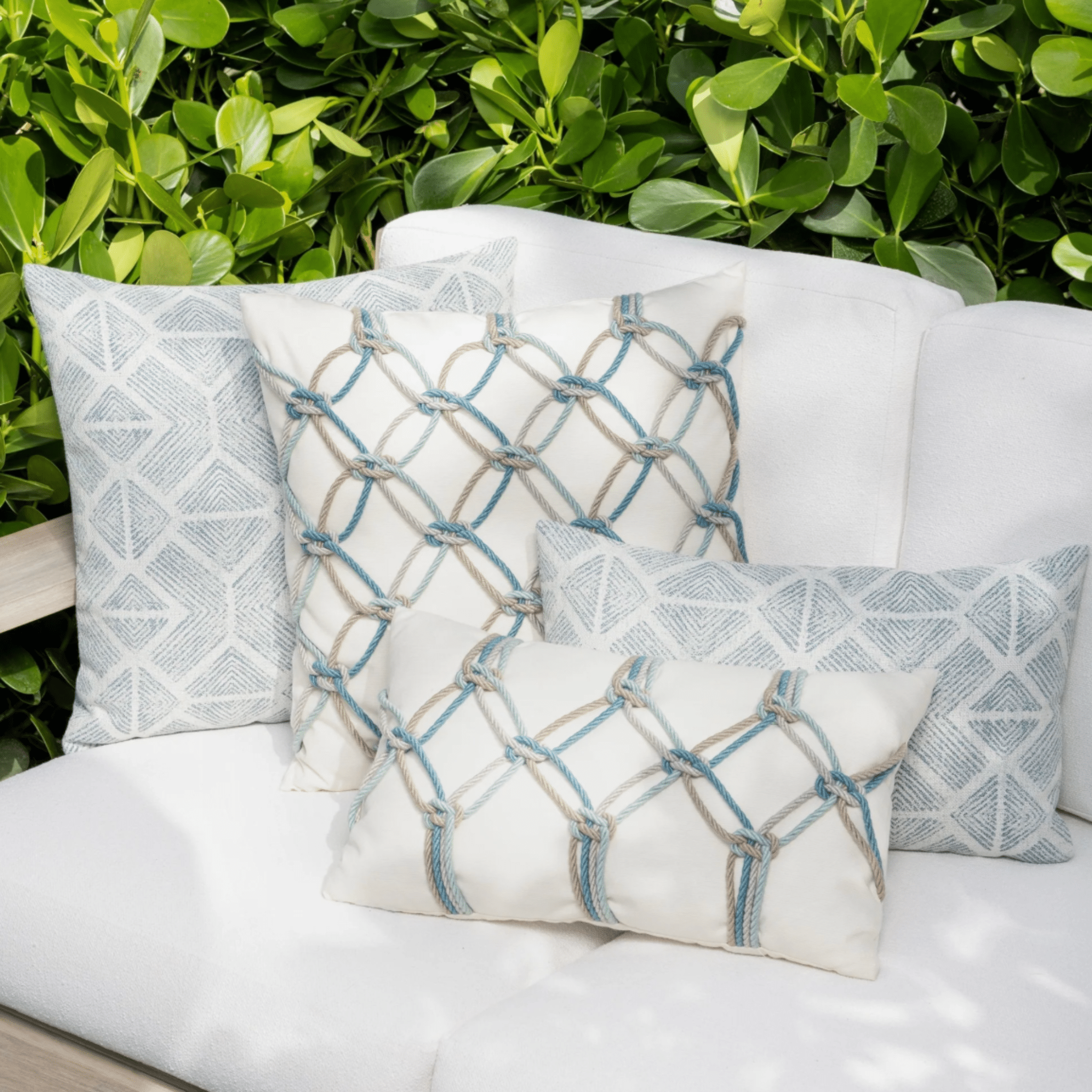aqua rope knot indoor outdoor pillow styled on outdoor seating in coastal patio lifestyle