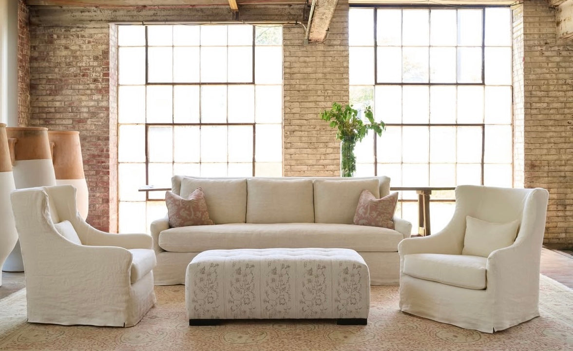Beige living room furniture set with a large window in the background. Our Boat House